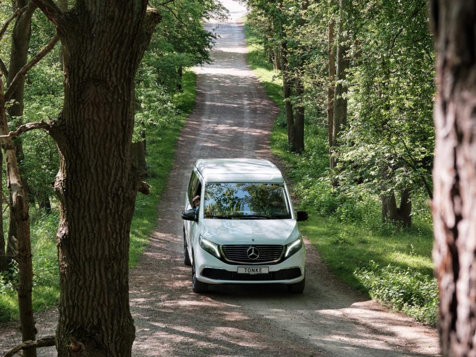 A van driving down a pathway surrounded by trees.