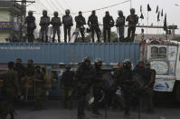 Police officers stand guard on a shipping container place on a road to stop the supporters of Tehreek-e-Labiak Pakistan, a radical Islamist political party, marching toward Islamabad, in Lahore, Pakistan, Friday, Oct. 22, 2021. Thousands of Islamists launched their "long march" from the eastern city of Lahore toward Pakistan's capital, demanding that the government release the leader of their Saad Rizvi, who was arrested last year amid demonstrations against France over publishing caricatures of Islam's Prophet Muhammad. (AP Photo/K.M. Chaudary)