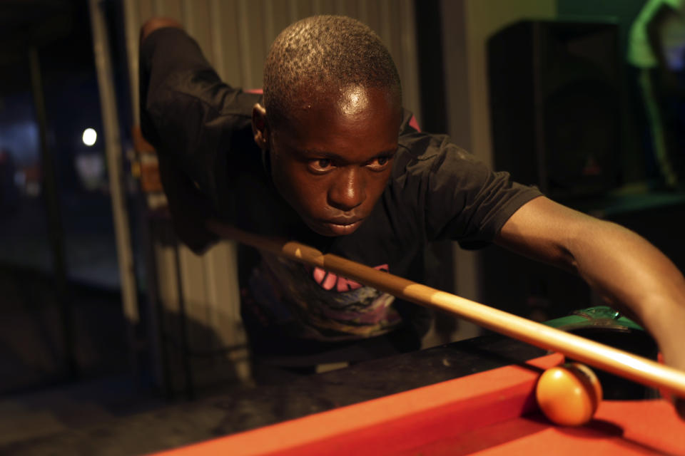 Levite Chisakarire, 18 years old, plays pool on the outskirts of Harare, Zimbabwe, Saturday. Nov, 19, 2022. Unable to further his education after finishing high school with low grades in 2019, Chisakarire struggled to find a job in Zimbabwe's stressed industries. Previously a minority and elite sport in Zimbabwe, the game has increased in popularity over the years, first as a pastime and now as a survival mode for many in a country where employment is hard to come by. (AP Photo/Tsvangirayi Mukwazhi)