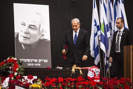 Israeli Prime Minister Benjamin Netanyahu (C) lays a rose on the coffin of Israeli singer Arik Einstein, depicted in the placard, during a memorial ceremony before his funeral at Rabin square in Tel Aviv November 27, 2013. REUTERS/Nir Elias