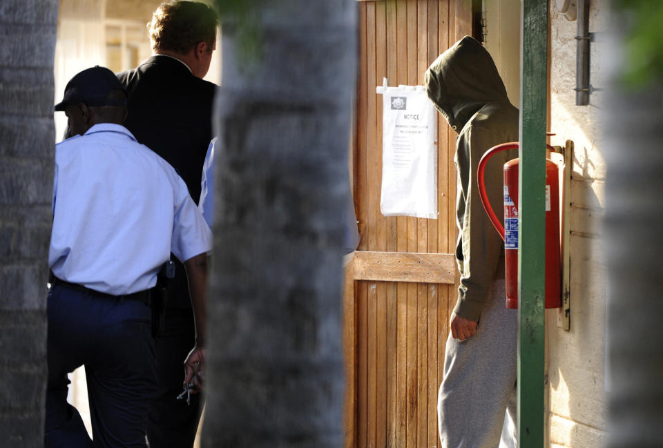 FILE: In this file photo taken Feb, 14, 2014 Olympic athlete Oscar Pistorius, right, heads to the holding cells at the Boschkop police station, east of Pretoria, South Africa. Pistorius goes on trial Monday, March 3, 2014 for the shooting death of his girlfriend Reeva Steenkamp. Prosecutors pressing the murder charge have listed 107 witnesses they're able to call and some will say that the world-famous athlete had a fight with Steenkamp and then intentionally killed her. (AP Photo-FILE)