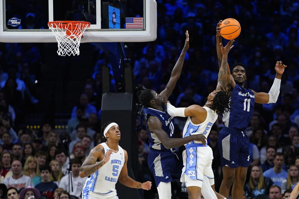 North Carolina's Caleb Love (2) cannot get a shot past St. Peter's KC Ndefo (11) and Fousseyni Drame (10) during the first half of a college basketball game in the Elite 8 round of the NCAA tournament, Sunday, March 27, 2022, in Philadelphia. (AP Photo/Chris Szagola)