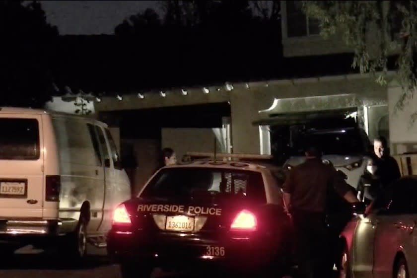 Police officers investigate the scene where a woman's body was found stuffed in a refrigerator.