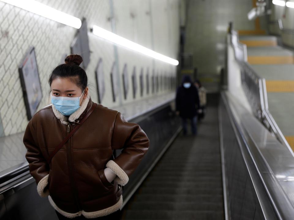 A woman wearing a face mask rides an escalator at an underpass leading to a subway station in the morning after the extended Lunar New Year holiday caused by the novel coronavirus outbreak, in Beijing, China February 10, 2020.  REUTERS/Carlos Garcia Rawlins