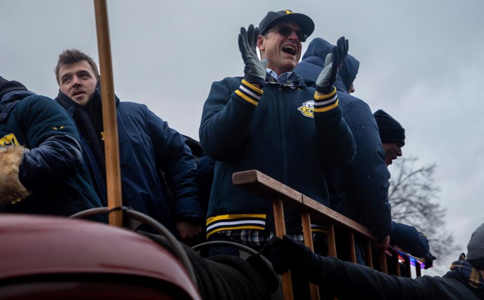 Michigan's Trevor Keegan, left, and Jim Harbaugh celebrate with the fans during a parade at the University of Michigan campus in Ann Arbor on Saturday, Jan. 13, 2024.