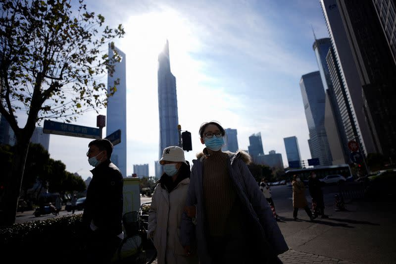 People wearing protective masks walk on a street, following new cases of COVID-19, in Shanghai