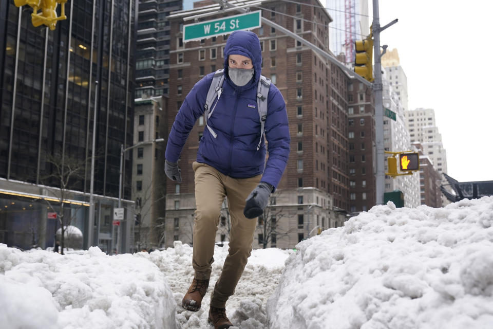A man tries to keep his balance as he makes his way around mounds of snow in midtown Manhattan, New York, Tuesday, Feb. 2, 2021. Tuesday's snowfall comes as residents of the New York City region are digging out from under piles of snow that shut down public transport, canceled flights and closed coronavirus vaccination sites. (AP Photo/Seth Wenig)