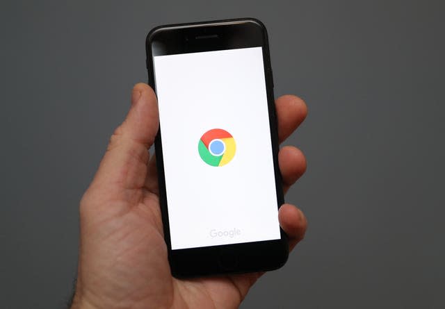 A person holds an iphone showing the app for Google chrome