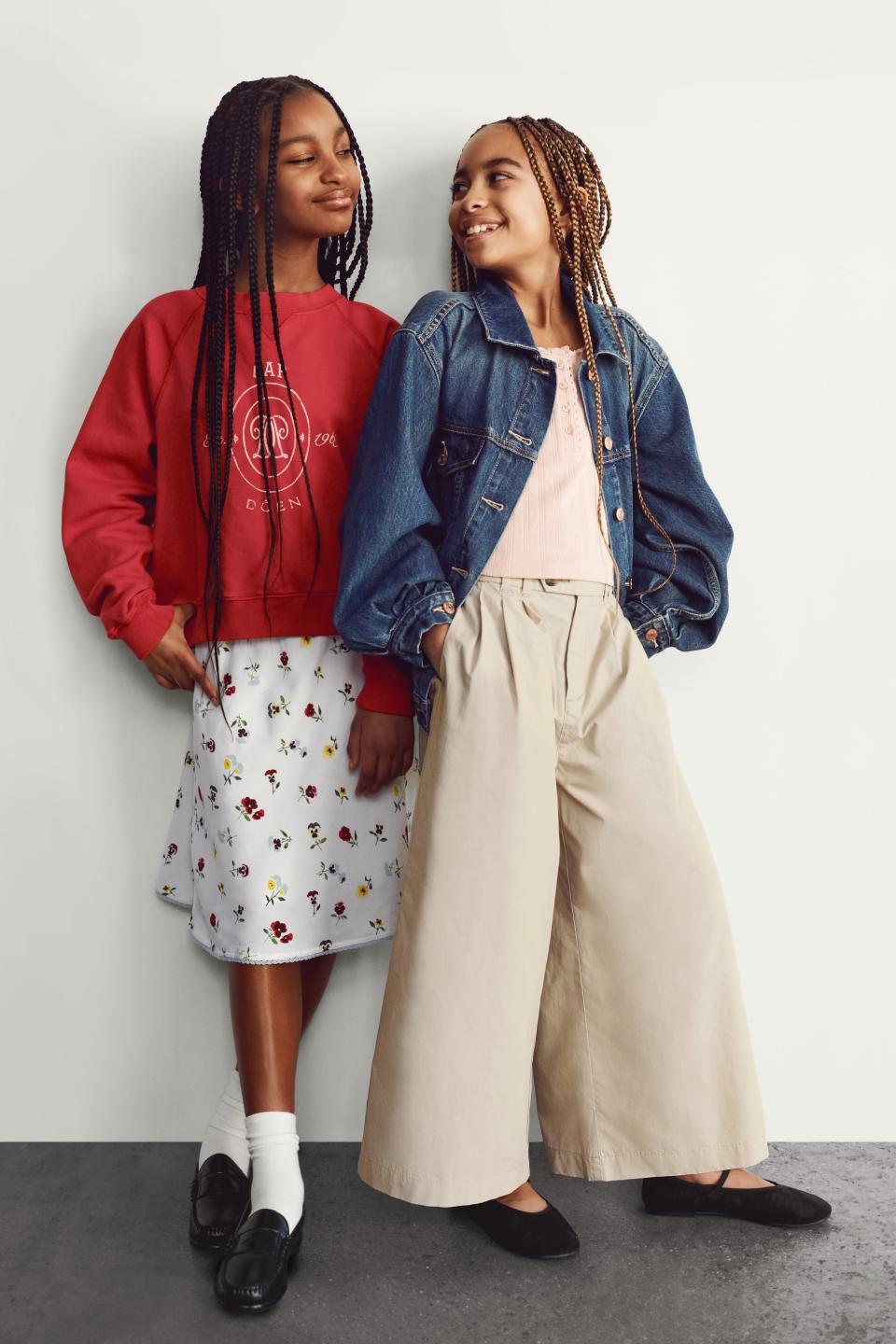 Two sisters wearing the gap x doen collaboration for kids in front of a plain wall