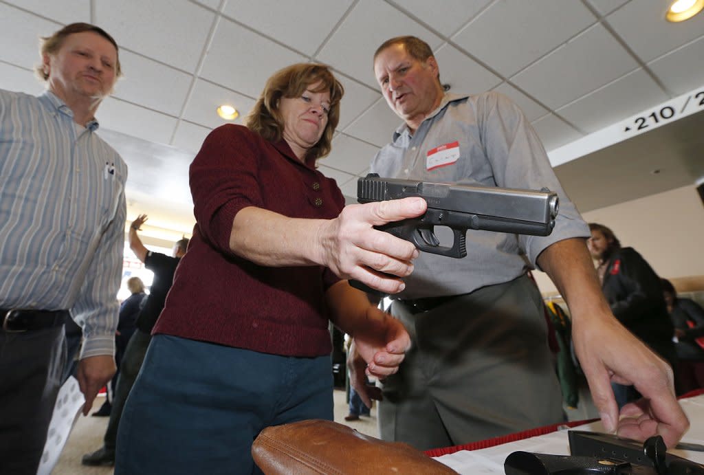 A woman holds a handgun in a fIrearms training class.