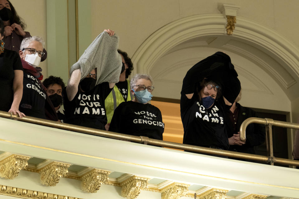 Protesters unveil their t-shirts with messages calling for a cease-fire in Gaza disrupt the first day of the California legislative session in Sacramento, Calif., Wednesday, Jan. 3, 2024. The Assembly session was just getting started when protesters wearing matching black t-shirts stood up in the gallery and started singing "Cease-fire now" and "Let Gaza Live." The Assembly adjourned the session.(AP Photo/Rich Pedroncelli)