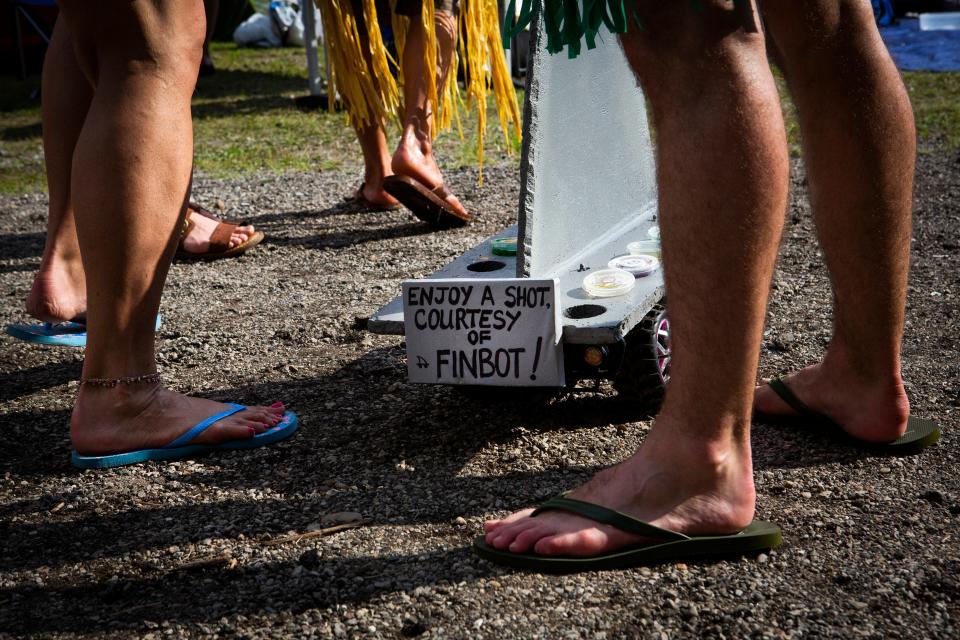 A remote controlled shark fin says: "Enjoy a shot courtesy of Finbot," as it is driven around with free jello shots at the tailgating event before the Jimmy Buffett & The Coral Reefer Band concert at Riverbend Music Center on Thursday, July 18, 2019.