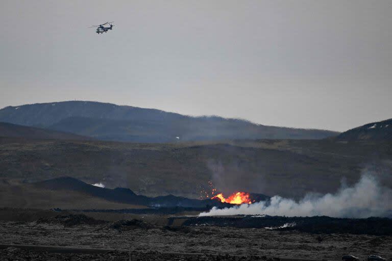 Un helicóptero de la Guardia Costera de Islandia vuela sobre una zona con lava incandescente cerca de la ciudad suroccidental islandesa de Grindavik después de una erupción volcánica el 15 de enero de 2024.