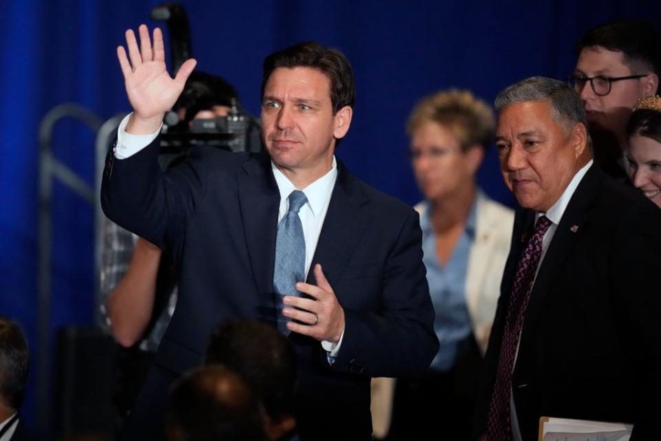 Florida Gov. Ron DeSantis, left, waves to the audience while arriving with Chris Ager, chairman of the New Hampshire Republican Party, during a stop at a New Hampshire Republican Party dinner, Friday, April 14, 2023, in Manchester, N.H.