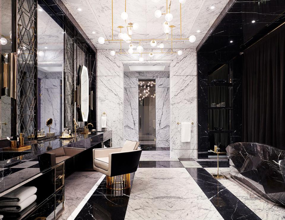 The master bath features a Nero Marquina marble vanity and tub. Custom chandelier by Lumifer; Brabbu sconces; chair by Rafauli.