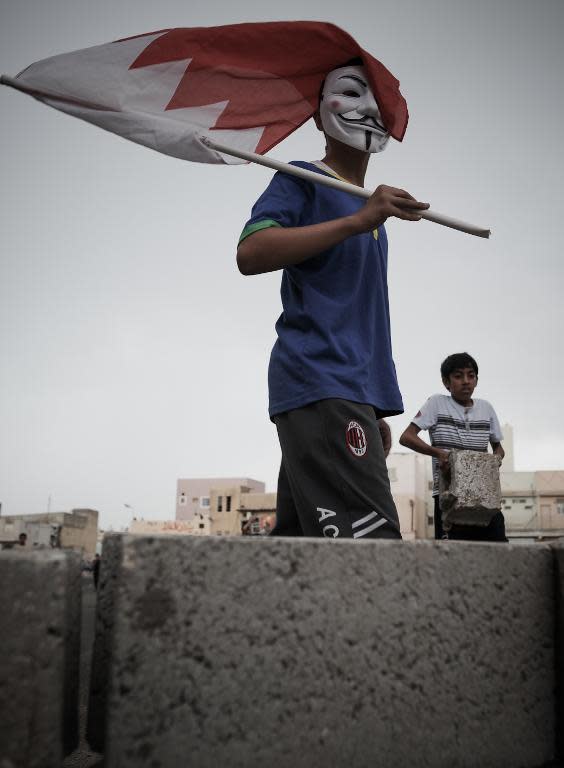 A Bahraini protestor holds a national flag wearing a mask used by the Anonymous movement during a protest against the arrival of Bahrain Formula One Grand Prix on April 18, 2013