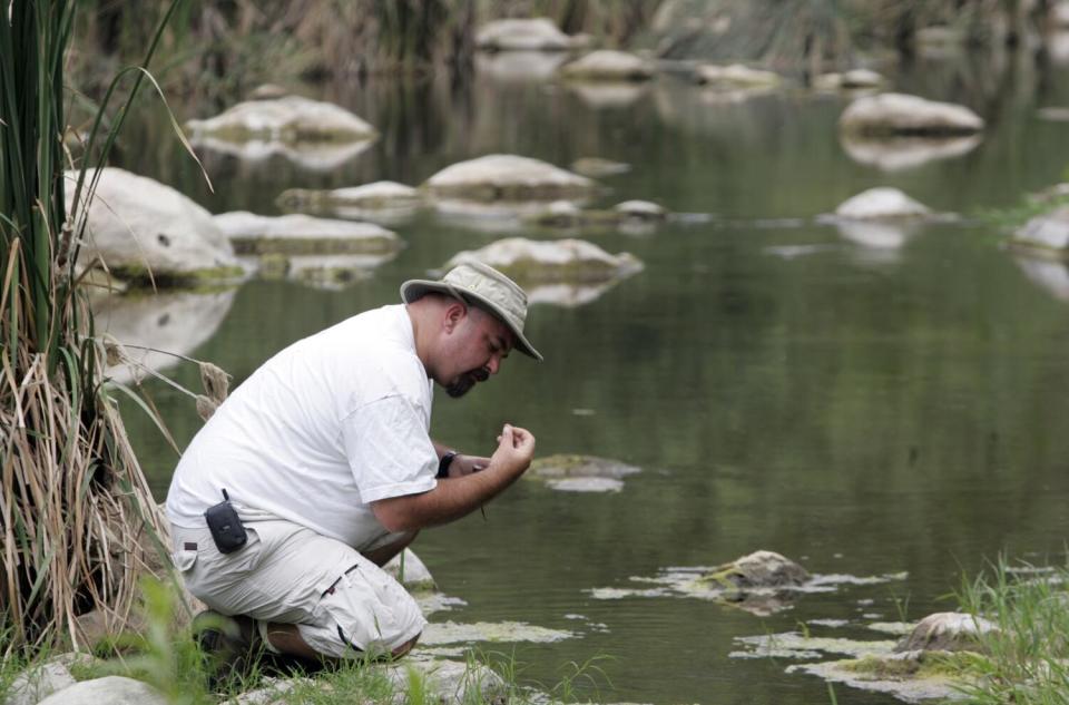 Mark Abramson kneels beside Malibu Creek.