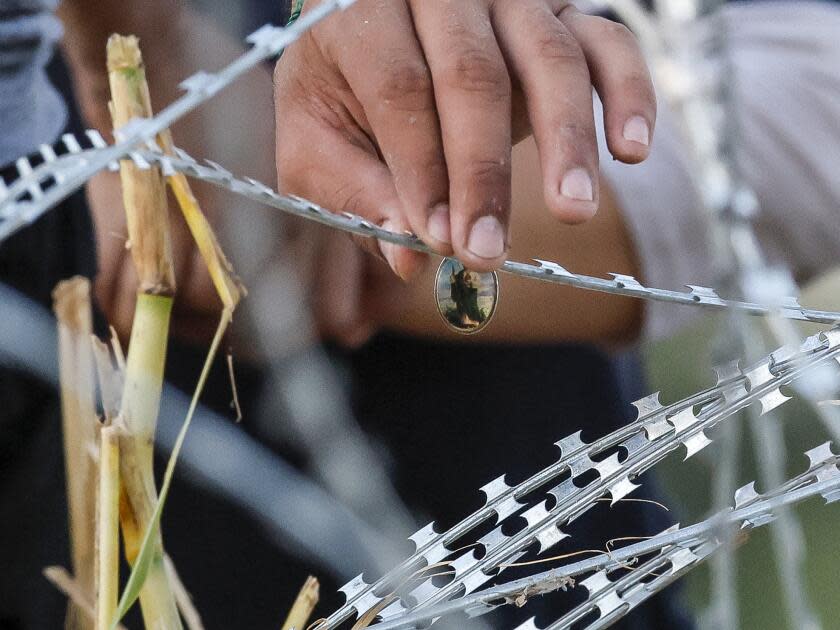 A hand gingerly touches razor wire.