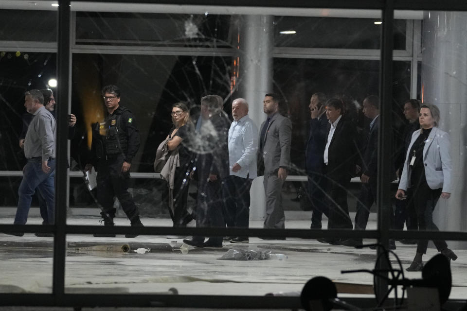 Brazil's President Luiz Inacio Lula da Silva, center, inspects the damage at Planalto Palace after it was stormed by supporters of Brazil's former President Jair Bolsonaro in Brasilia, Brazil, Sunday, Jan. 8, 2023. Protesters who refuse to accept Bolsonaro´s election defeat stormed Congress, the Supreme Court and presidential palace in the capital, a week after the inauguration of his rival, President Luiz Inacio Lula da Silva. (AP Photo/Eraldo Peres)