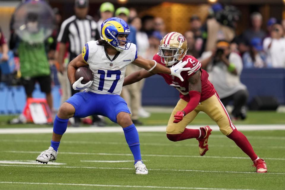 Puka Nacua tries to fend off 49ers cornerback Deommodore Lenoir after the Rams receiver made a catch.