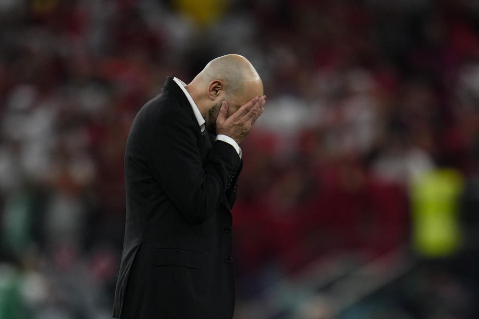 Morocco's head coach Walid Regragui cover his face after his team defeated Belgium 2-0 in a World Cup group F soccer match at the Al Thumama Stadium in Doha, Qatar, Sunday, Nov. 27, 2022. (AP Photo/Manu Fernandez)