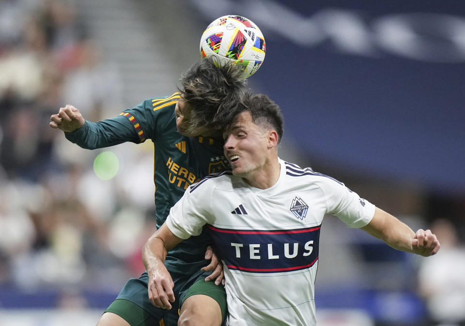 LA Galaxy's Miki Yamane, left, and Vancouver Whitecaps' Alessandro Schopf collide while vying for the ball during the first half of an MLS soccer match Saturday, April 13, 2024, in Vancouver, British Columbia. (Darryl Dyck/The Canadian Press via AP)