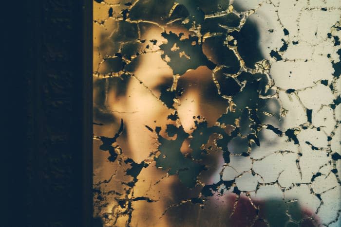 A woman's reflection in a cracked mirror