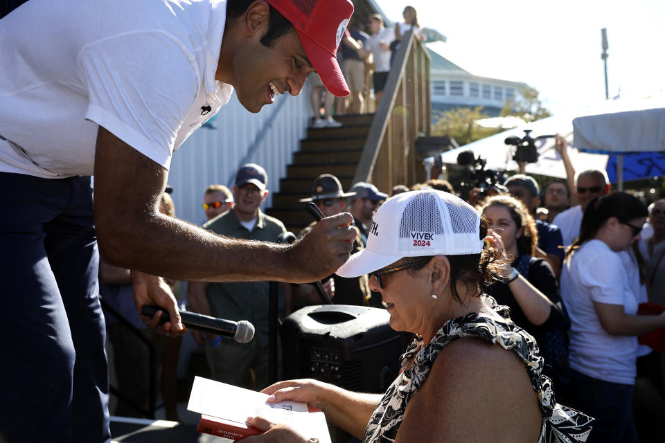 Republican presidential candidate Vivek Ramaswamy signs a supporter's hat at the Iowa State Fair.