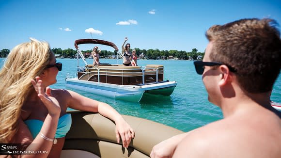 Couples waving to passing pontoon boat