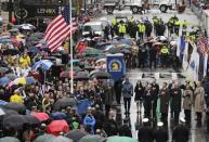 Survivors, officials, first responders and guests pause as the flag is raised at the finish line during a tribute in honor of the one year anniversary of the Boston Marathon bombings, Tuesday, April 15, 2014 in Boston. (AP Photo/Charles Krupa)