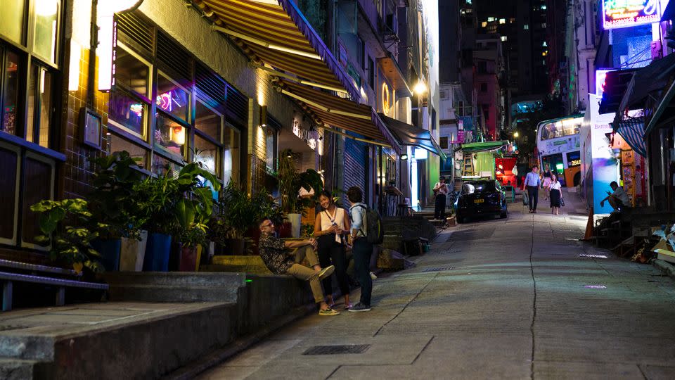 People gather outside a restaurant on a near-empty street in the Soho area of Hong Kong. - Noemi Cassanelli/CNN