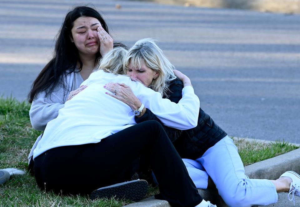 Former Covenant School students Ashley Crafton, top left, and Josephine Horn comfort their former six grade teacher, Lisa Horn, right, at a makeshift memorial by the entrance of the Covenant School Tuesday, March 28, 2023, in Nashville, Tenn. 