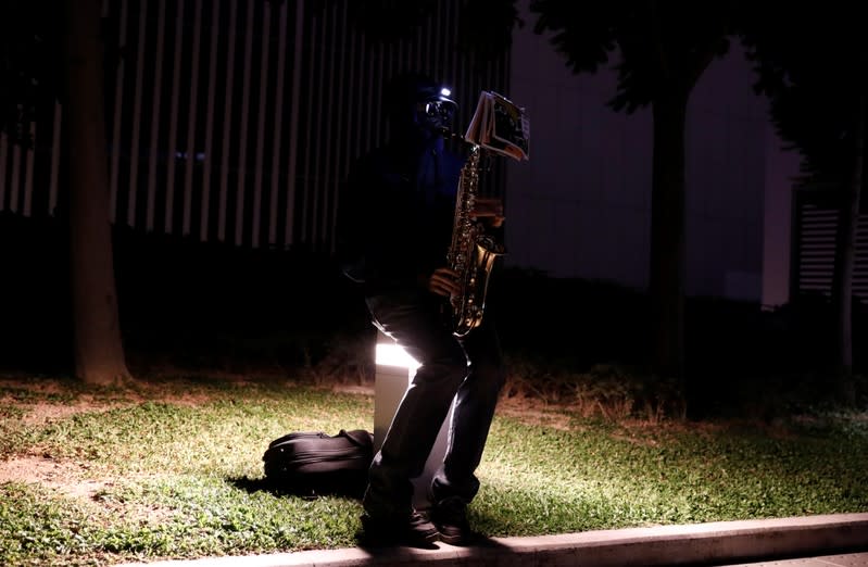 A man plays the saxophone in Tamar Park during a prayer and remembrance ceremony in Hong Kong