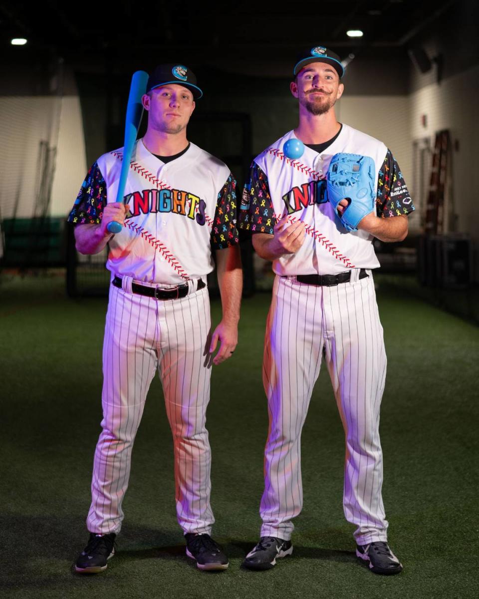 Charlotte Knights outfielder Zach DeLoach and pitcher Aaron McGarity pose in their new jerseys designed by 11-year-old Brantlee Mumford.