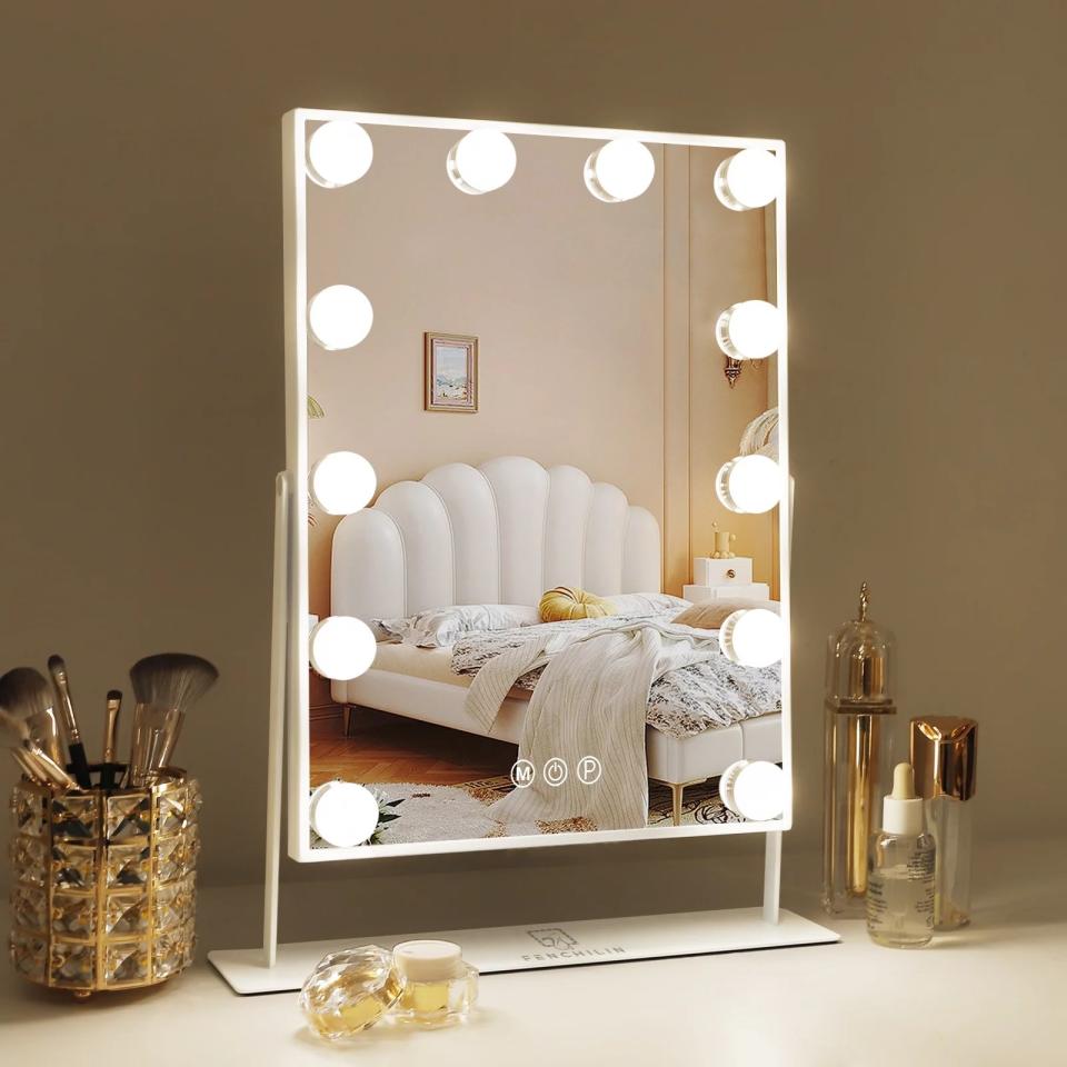 lighted vanity mirror on top of white desk with makeup brushes