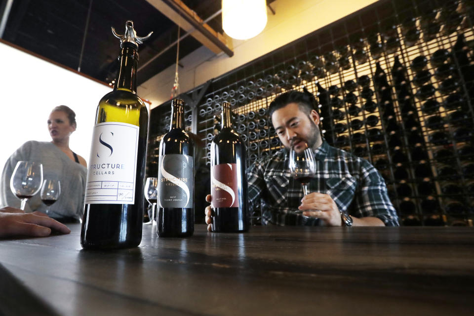 In this photo taken Thursday, Nov. 21, 2019, Mike Roh sniffs wine before tasting it at Structure Cellars wine tasting room in Seattle, Wash. From less than 20 wineries in 1981, the Washington wine industry has grown to more than 1,000 this year. The state is the second-largest producer of premium wines in the U.S., trailing only California. (AP Photo/Elaine Thompson)