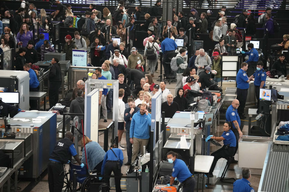 Several dozen passengers and airport workers seen from above at a security checkpoint.