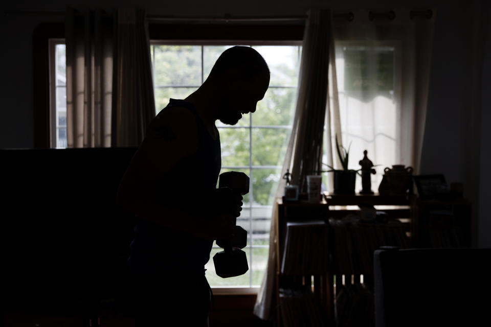 Christian Hainds works out at his home in Hammond, Ind., Monday, June 7, 2021. Health officials have warned since early on in the pandemic that obesity and related conditions such as diabetes were risk factors for severe COVID-19. It wasn't until he was diagnosed as diabetic around the start of the pandemic that he felt the urgency to make changes. Hainds lost about 50 pounds during the pandemic, and at 180 pounds and 5 feet, 11 inches tall is no longer considered obese. (AP Photo/Shafkat Anowar)