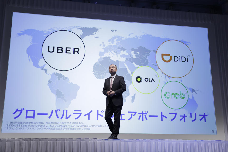 Masayoshi Son stands in front of a map showing the impressive collection of global ride-sharing startups SoftBank has come to be invested in. (Kiyoshi Ota/Bloomberg via Getty Images)