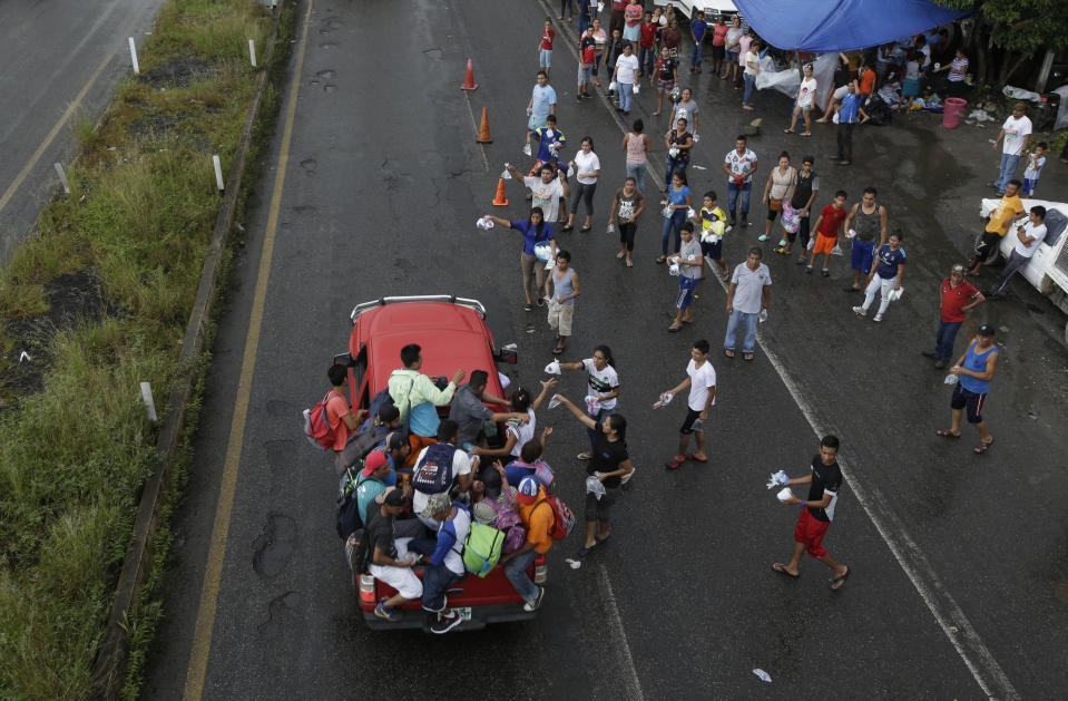 Mexicans from religious organizations hand out small bags containing water, toilet paper, diapers and medicine to Central American migrants who got a free ride from a motorist, in Xochiltepec, Mexico, Monday, Oct. 22, 2018. Motorists in pickups and other vehicles have been offering the Central American migrants rides, often in overloaded truck beds, as the group of about 7,000 people heads to the U.S. border. (AP Photo/Moises Castillo)