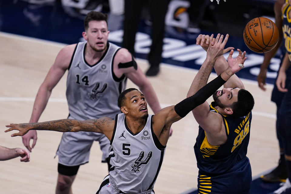 San Antonio Spurs guard Dejounte Murray (5) goes up for a rebound over Indiana Pacers center Goga Bitadze (88) during the second half of an NBA basketball game in Indianapolis, Monday, April 19, 2021. (AP Photo/Michael Conroy)