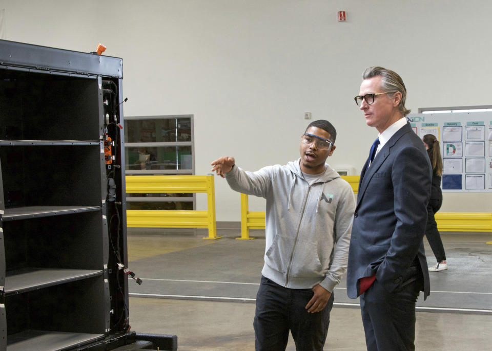 In this photo provided by the California Governor's Office, Gov. Gavin Newsom, right, talks to a MOXION employee Thursday, May 25, 2023, in Richmond, Calif. Newsom toured the battery manufacturing plant and touted his updated plan to ease the permitting process for new clean energy projects. (Sheila Fitzgerald/California Governor's Office via AP)