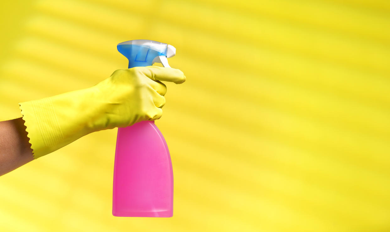 Hand holding a bottle of cleaning spray.