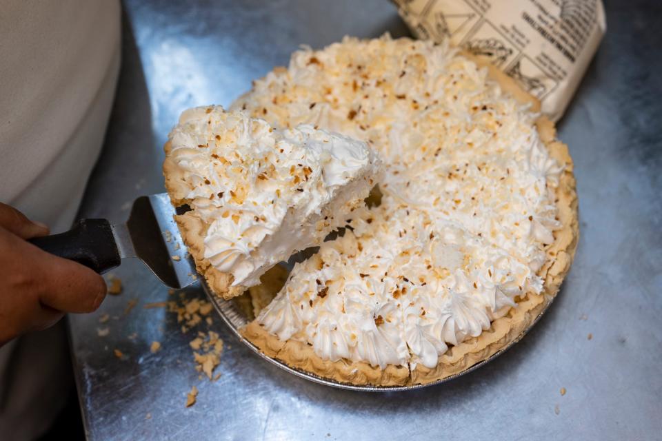 A server cuts a slice of coconut cream pie for a to-go order on Saturday, July 16, 2022, at Steer-In in Indianapolis.