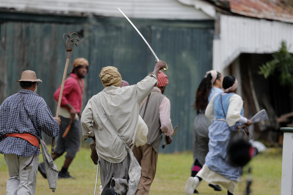 People participate in a performance artwork reenacting the largest slave rebellion in U.S. history in LaPlace, La., Friday, Nov. 8, 2019. The reenactment was conceived by Dread Scott, an artist who often tackles issues of racial oppression and injustice. Scott says that those who took part in the 1811 rebellion were "heroic" and that the rebellion is something that people should know about and be inspired by. (AP Photo/Gerald Herbert)