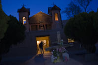 Pilgrims begin to arrive on the church steps ahead of Good Friday as dusk envelopes El Santuario de Chimayo, Thursday, April 17, 2014. El Santuario de Chimayo, was built by the Spanish in 1813. (AP Photo/Jeremy Wade Shockley)