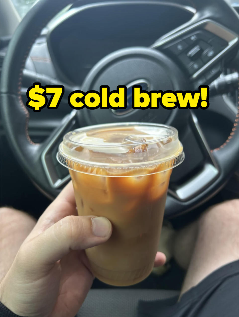 Person holding an iced coffee in a car with overlay text saying $7 cold brew
