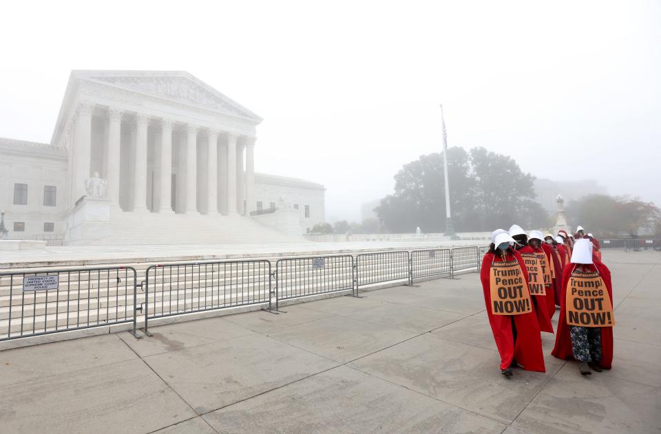 On a foggy morning, protesters with the “Handmaids Brigade” march outside the U.S. Supreme Court prior to a hearing held by the Senate Judiciary Committee to vote on the nomination of Judge Amy Coney Barrett on October 22, 2020, in Washington, DC.