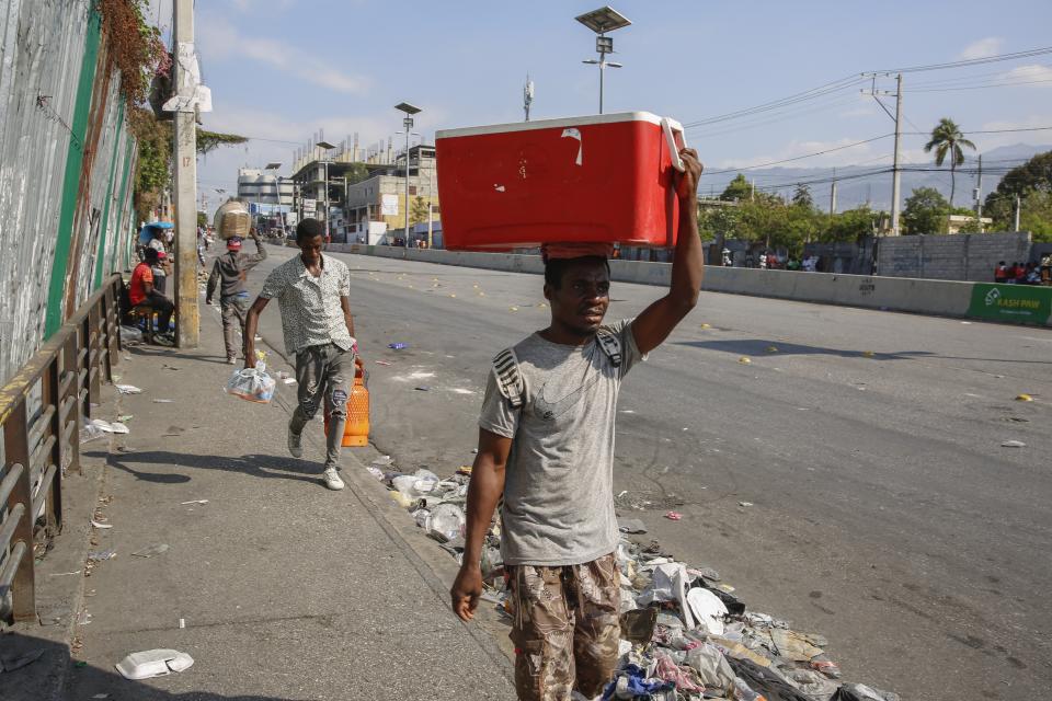 People walk along a street in Port-au-Prince, Haiti, Wednesday, March 13, 2024. (AP Photo/Odelyn Joseph)