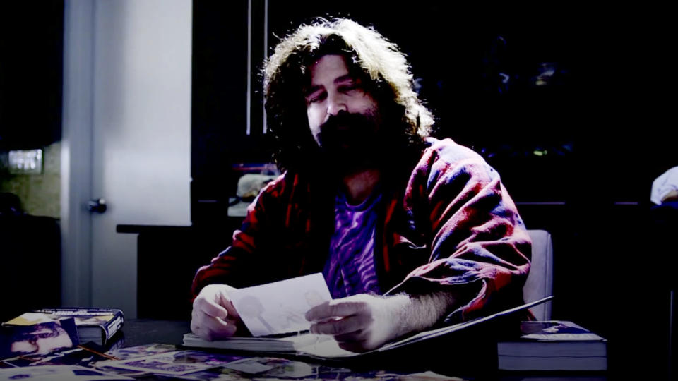 Mick Foley looking at photos in For All Mankind: The Life And Career Of Mick Foley